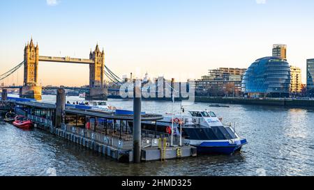 Sonnenuntergang auf der Tower Bridge mit Rathaus. City Cruises Boot. Stockfoto
