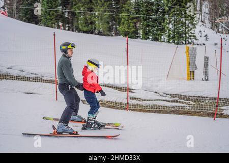 Junge lernt Skifahren, trainiert und hört seinem Skilehrer im Winter auf der Piste zu Stockfoto