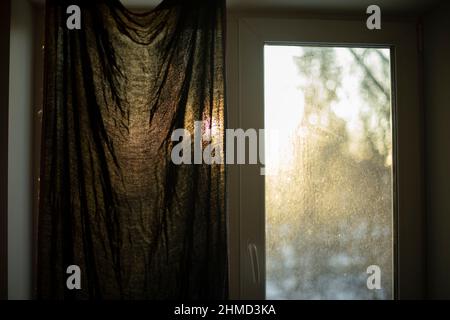 Fenster am Morgen. Der Vorhang schließt sich vor Licht. Dämmerung durch Stoff. Kunststofffenster in der Wohnung. Stockfoto