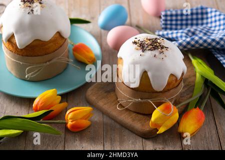 Traditioneller Osterkuchen, bunte Eier und Tulpen auf Holztisch Stockfoto