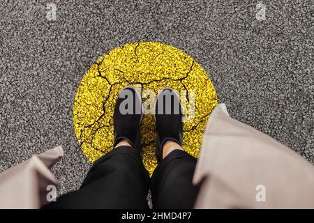 Frauenbeine in schwarzen Schuhen stehen auf einem gelben Kreis der Straße, Draufsicht. Verlassen Sie Ihre Komfortzone für die persönliche Entwicklung Stockfoto