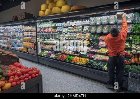 Ein Arbeiter füllt die Regale im Gemüsebereich von Citarella's, einem gehobenen Supermarkt auf der 6th Avenue in Greenwich Village, New York City, auf. Stockfoto