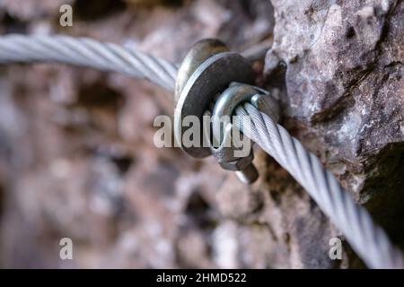 Nahaufnahme einer Handschiene entlang eines schwierigen Wanderweges in der Fränkischen Schweiz, Deutschland, aus Stahlseil mit montiertem Seilclip Stockfoto