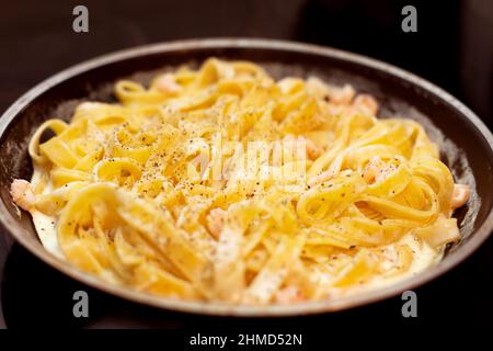 Tagliatelle Pasta mit Garnelen mit Sauce in der Pfanne. Italienische Gerichte werden zubereitet Stockfoto