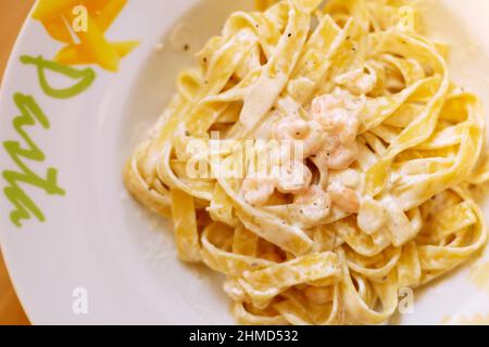 Tagliatelle Pasta mit Garnelen mit Sauce in der Draufsicht des Tellers. Italienisches Gericht Stockfoto