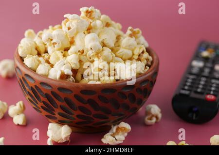Popcorn- und TV-Fernbedienung auf rotem Hintergrund Stockfoto