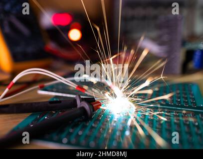 Auf dem Holztisch eines talentierten Ingenieurs liegt ein dunkelgrüner Elektronik-Chip für TFT mit hellen, mehrfarbigen Drähten und funkelt witzig Stockfoto