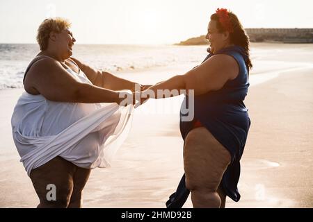 Kurvige Frauen, die am Strand tanzen, haben Spaß während der Sommerferien - konzentrieren Sie sich auf Gesichter Stockfoto