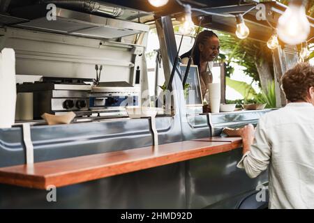 African Senior Woman Serving take away Food inside Food Truck - Focus on man Food box Stockfoto