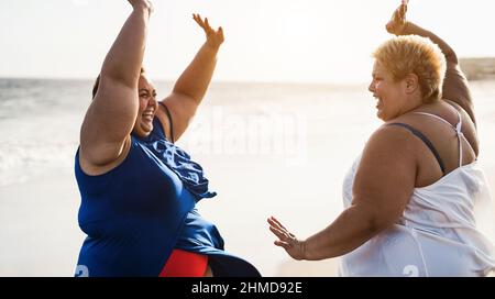 Kurvige Frauen tanzen am Strand Spaß während der Sommerferien - Fokus auf das richtige Gesicht Stockfoto