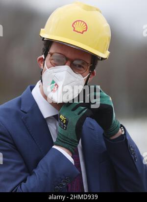 09. Februar 2022, Nordrhein-Westfalen, Köln: Hendrik Wüst (CDU), Ministerpräsident von Nordrhein-Westfalen, lässt sich beim Baubeginn einer CO2-neutralen Bio-Flüssigerdgas-Anlage (Bio-LNG) auf dem Raffineriestandort Shell einen Helm aufsetzen. Die Anlage soll ab Mitte 2 2023 rund 100.000 Tonnen Bio-LNG pro Jahr für den Schwerlasttransport produzieren. Foto: Oliver Berg/dpa Stockfoto