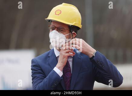 09. Februar 2022, Nordrhein-Westfalen, Köln: Hendrik Wüst (CDU), Ministerpräsident von Nordrhein-Westfalen, lässt sich beim Baubeginn einer CO2-neutralen Bio-Flüssigerdgas-Anlage (Bio-LNG) auf dem Raffineriestandort Shell einen Helm aufsetzen. Die Anlage soll ab Mitte 2023 rund 100.000 Tonnen Bio-LNG pro Jahr für den Schwerlasttransport produzieren. Foto: Oliver Berg/dpa Stockfoto