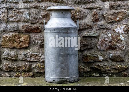 Milch wird an einer Steinmauer abgelassen Stockfoto