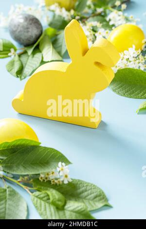 Happy Easter Konzept mit Kaninchen, natürlich bunten ostereiern und Frühlingsblumen auf blauem Hintergrund. Osterhintergrund. Stockfoto