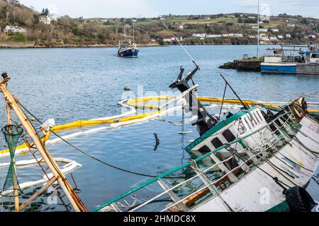 Union Hall, West Cork, Irland. 9th. Februar 2022. Der Fischtrawler „Scepter“ sank, während er am Keelbeg Pier in der Union Hall am Sonntagabend festgemacht wurde. LCF Marine aus Castletownbere überwacht das Schiff auf Ölverschmutzung und ersetzt heute die Booms um das Boot herum, um die Ölpest im Hafen einzudämmen. Das Fischerboot „Providence II“ nähert sich dem Kai, während die Arbeit am versunkenen Trawler fortgesetzt wird. Quelle: AG News/Alamy Live News Stockfoto