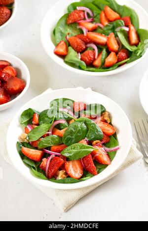 Leckerer Obstsalat mit Erdbeere, roter Zwiebel und Spinat in einer Schüssel Stockfoto