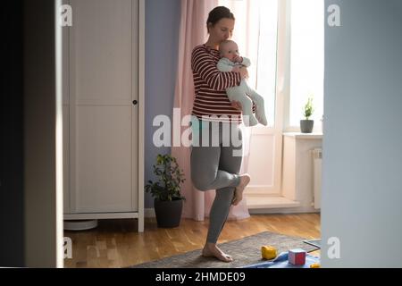 Mutter mit Baby macht Yoga zu Hause, um stark und gesund zu sein Stockfoto
