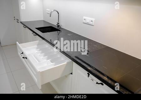 Seitenansicht Moderne und elegante Küche mit weißen Schubladen und Schränken, offene Küchenschublade mit Spültrockner, selektiver Fokus Stockfoto