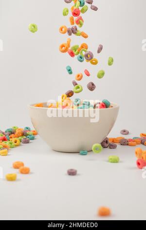 Bunte Müslibox für das Frühstück am Morgen. Maisflocken fallen in die weiße Schüssel. Bewegung. Copyspace. Stockfoto