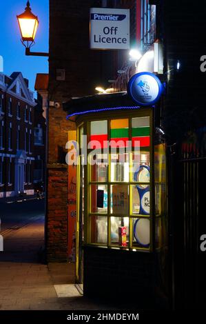 Ein alter Laden mit beleuchtetem Erkerfenster und Laterne in der Abenddämmerung Stockfoto