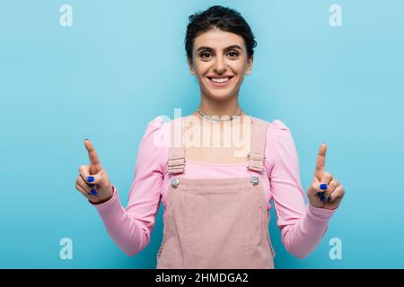 Vorderansicht einer fröhlichen Frau, die mit den Fingern auf Blau zeigt Stockfoto