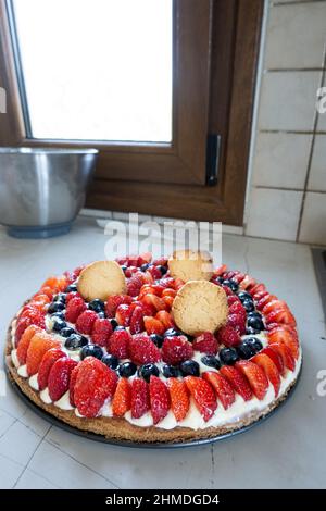 Tarte mit Erdbeere, Himbeere, Heidelbeere und Schlagsahne in der Küche Stockfoto