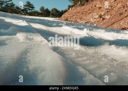 Reifenpanne und einige Fußabdrücke auf Schnee in der Wintersaison. Stockfoto