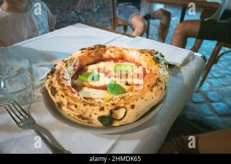 Nahaufnahme der neapolitanischen Pizza margherita mit Basilikum auf dem Tisch im Restaurant Stockfoto