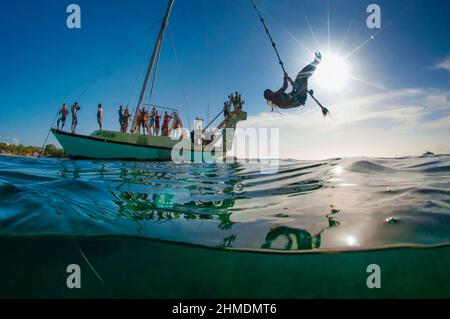 Menschen schwingen von einem Boot im karibischen Ozean Stockfoto
