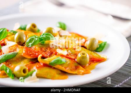 Ravioli-Pasta mit Tomatensauce, Oliven und Basilikum Stockfoto