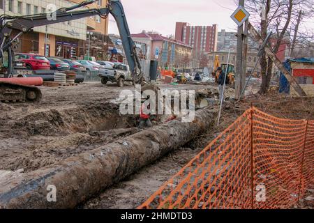 Dnipropetrovsk, Ukraine - 11.30.2021: Bauarbeiten zur Verlegung von Kanalrohren in städtischen Gebieten. Traktor- und Baggerarbeiten. Stockfoto