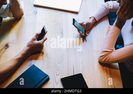 Freunde sitzen am Tisch und nutzen Smartphones Stockfoto