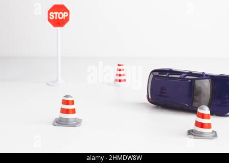 Absturz. Schilder und Kegel auf der Straße. Leitplanke auf der Fahrbahn. Fahrgefahr. Umgedrehter Wagen. Kollision. Stockfoto