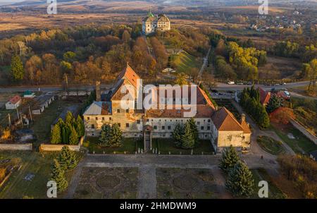 Luftaufnahme des Kapuzinerklosters 1737 Jahre römisch-katholische Kirche St. Antonius bei Sonnenuntergang, im Hintergrund der Burg im Dorf Olesko, Ukraine Stockfoto