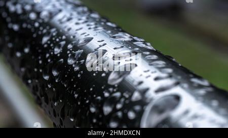 Wassertropfen auf einer nassen Metallschiene nach einigen starken Regenfällen Stockfoto