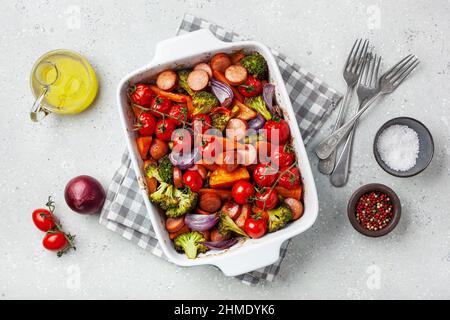 Im Ofen gebackenes Gemüse und Würstchen, gesundes Mittagessen, Süßkartoffel Zwiebel Tomate Brokkoli Stockfoto