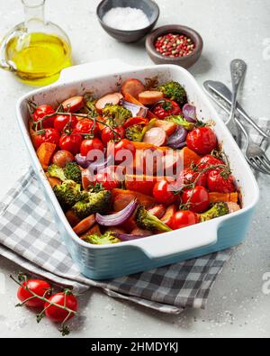 Im Ofen gebackenes Gemüse und Würstchen, gesundes Mittagessen, Süßkartoffel Zwiebel Tomate Brokkoli Stockfoto