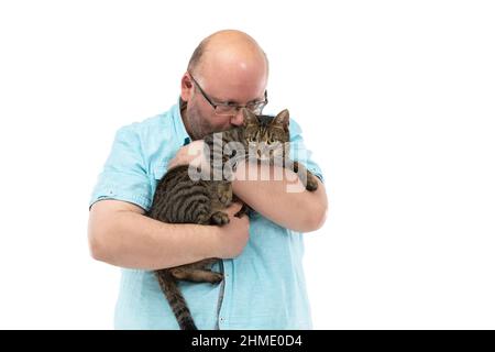 Ein kahler Mann hält eine Katze in den Armen und küsst ihn. Stockfoto