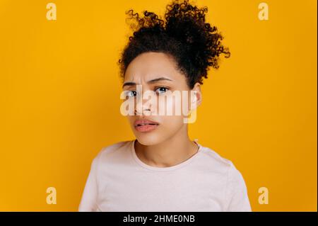 Verwirrt, aufgeregt, verwirrt afroamerikanische junge Frau, mit lockigem Haar, schaut fragend auf die Kamera, kann nicht verstehen, steht über einem isolierten rosa Hintergrund Stockfoto