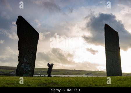 Stenness, Orkney, Großbritannien. 9th. Februar 2022. Ein einnehmender Besucher der Stones of Stenness - einem neolithischen Steinkreis - in Orkney, Schottland, trotzt dem eiskalten Wind am späten Nachmittag. Kredit: Peter Lopeman/Alamy Live Nachrichten Stockfoto