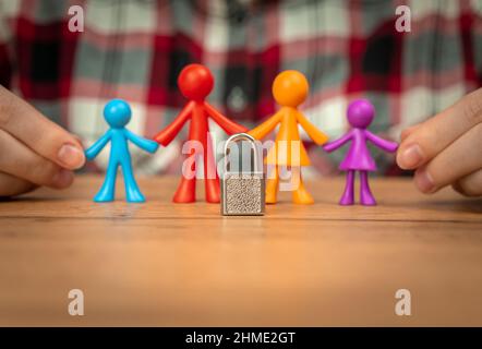 Familienprobleme, bunte Plastikfiguren auf Holztisch mit Vorhängeschloss. Scheidung in der Familie mit Kindern, Konflikt, Krisenkonzept Stockfoto