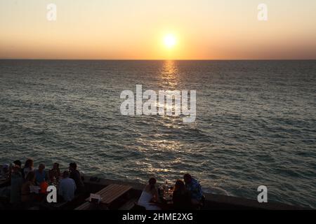 In Bidart, Pays Basque, Frankreich, genießen Menschen einen Drink oder ein Essen im Freien, während sie den Sonnenuntergang über dem Atlantik beobachten Stockfoto