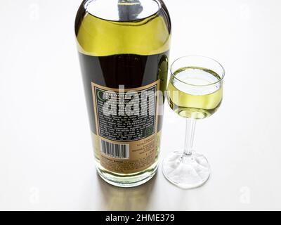 Moskau, Russland - 3. Februar 2022: Rückseite der Flasche mit grünem Chartreuse-Likör aus den USA und Likörglas auf hellem Tisch. Der Likör wurde hergestellt Stockfoto