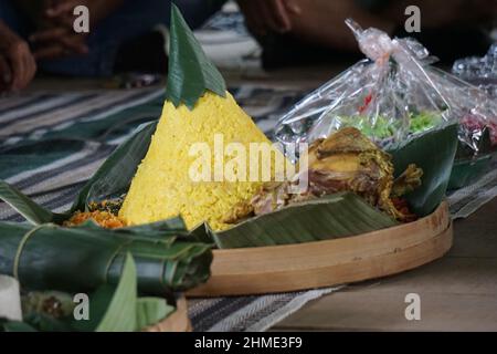 Indonesisches Dankesmenü mit dem Namen Nasi tumpeng (Reis mit Kegelform). Nasi tumpeng essen in der Regel auf Geburtstagsparty, Abschlussfeier oder Danksagn Stockfoto