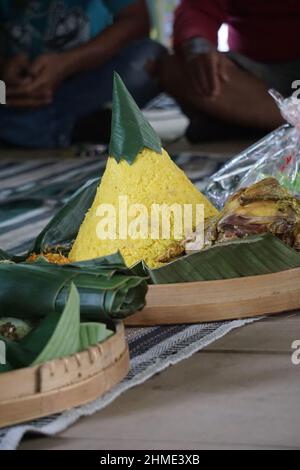 Indonesisches Dankesmenü mit dem Namen Nasi tumpeng (Reis mit Kegelform). Nasi tumpeng essen in der Regel auf Geburtstagsparty, Abschlussfeier oder Danksagn Stockfoto