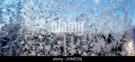 Schmelzendes Eis, das an einer Fensterscheibe entlang läuft, Nahaufnahme der gefrorenen Fensterscheibe mit Eiskristallen Stockfoto