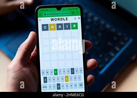 Ein Mann spielt mit dem Wortspiel Wordle aus der Nähe auf einem Handybildschirm auf der offiziellen App-Website in Barcelona, Spanien - 9. Februar 2022. Stockfoto