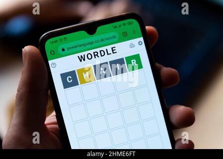 Ein Mann spielt mit dem Wortspiel Wordle aus der Nähe auf einem Handybildschirm auf der offiziellen App-Website in Barcelona, Spanien - 9. Februar 2022. Stockfoto