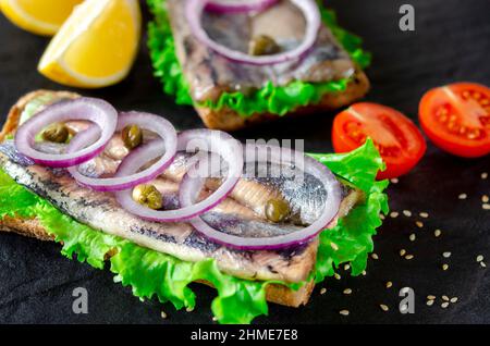 Sandwich mit Butter, Hering, roter Zwiebel und Thymian. Ein norwegischer junger Hering mit Salat Stockfoto