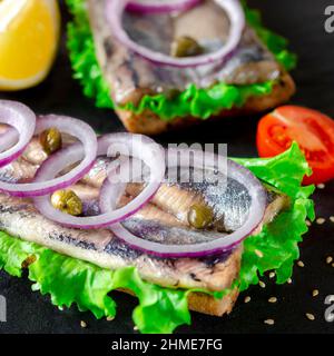 Sandwich mit Butter, Hering, roter Zwiebel und Thymian. Ein norwegischer junger Hering mit Salat Stockfoto